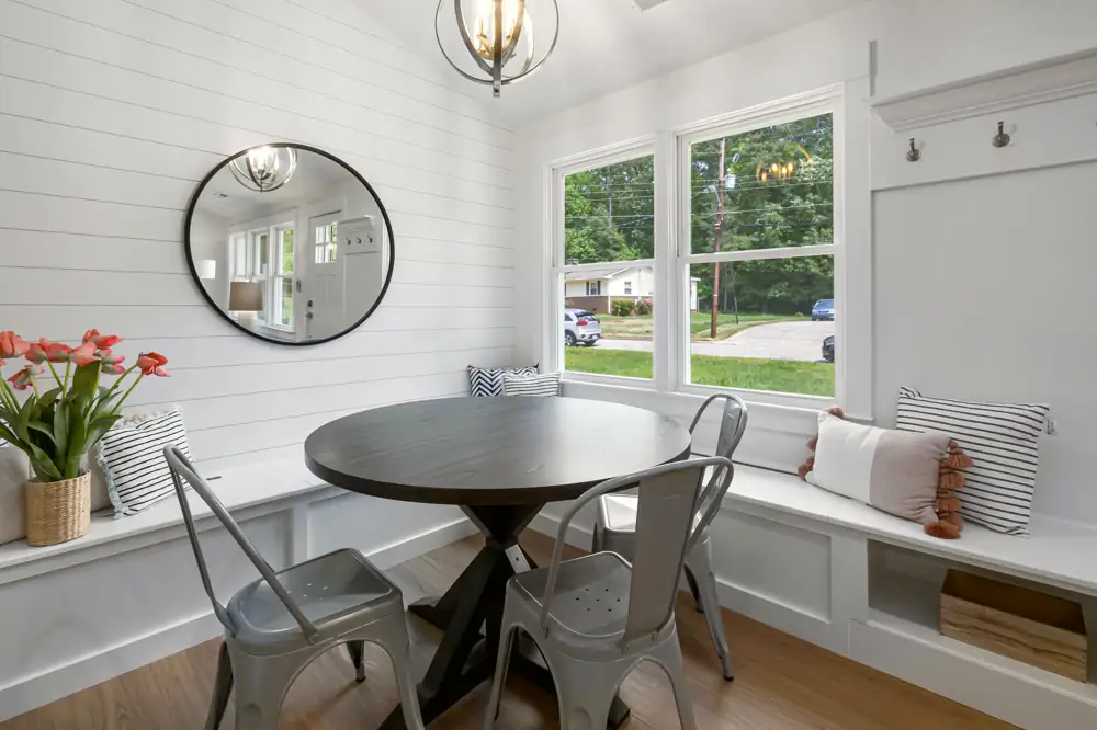The breakfast nook at Laurel Bend Ranch, a round table and a built-in window bench with storage against a shiplap wall.