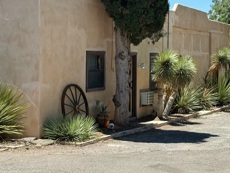 Mesquite Court Home, a single-story adobe-style house with tan stucco walls, yucca plants and a gravel edge.